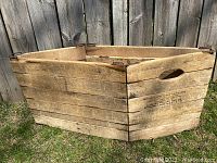 Full view of the unfolded wooden folding grocery box placed on grass showing rectangular shape, construction and folding metal hinges.