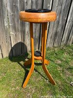 Full view of the vintage wooden hockey stick ashstand outdoors on grass with wood fence background, showing the structure and condition.
