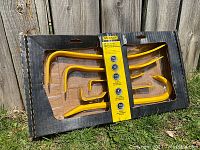 Display of the 5 yellow-coated pry bars arranged in original packaging against wooden backdrop.