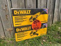Two sealed DeWalt grinder boxes stacked outdoors against wooden fence