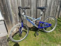 Side view of the full Pacific mountain bike showing silver and blue frame, knobby tires, aluminum rims and suspension fork.