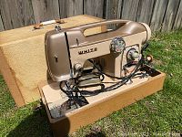 Sewing machine set into open hard case on grass