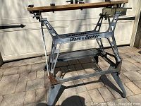 Front view of Black & Decker workbench showing metal frame with branding and wooden clamping top.