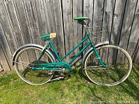 Side view of the full bicycle showing green frame, saddle, rear basket, front and rear tires and fenders.