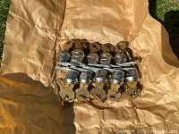 Photo showing 9 vintage locksets with attached brass-colored keys bundled with a rubber band on crumpled brown paper.