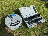 Maximum thin cut off wheels container next to impact sockets set in gray plastic case on grass surface.