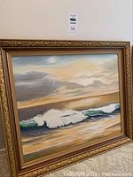 Framed ocean painting showing waves and cloudy sky, upright on floor against wall.