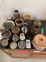 Overview photo showing 15 assorted pottery items in earthy tones arranged on a table, highlighting size and variety.