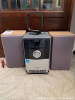 Full view of the Sony audio system including the central CD player/radio tuner and the two speakers with antenna on top.