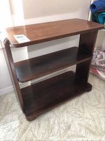 Front angle view of the vintage wooden bookshelf showing three shelves and side supports.