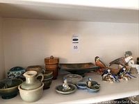 Front view of top shelf showing various celadon and glazed pottery, lidded jars, moorcroft tray and bird figurines