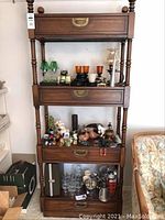 Full view of one Kaufman shelving unit with 3 drawers and one faux drawer, shelves filled with various glassware, decor items, and collectibles.