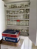 Glass Mason canning jars with lids arranged on cupboard shelves