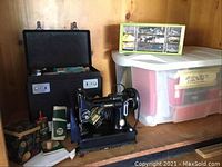 Overview of sewing machine, carrying case, and plastic bin of supplies