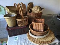 Overview of baskets piled on a white surface showing multiple shapes and sizes including handled and lined baskets.