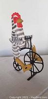 Front and side view of handcrafted rooster striped black and white riding a black metal bicycle decoration