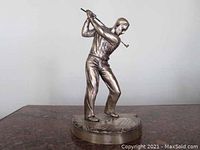 Silver statue of male golfer swinging club on round base, front angle