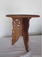 Side view showing the wooden legs with intricate carved floral and geometric patterns.