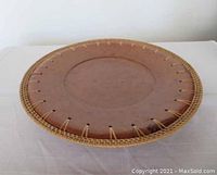 Side angle showing dark terracotta plate with woven edge detail
