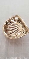Silver shell-shaped jewelry holder, seen from inside showing tarnish and dirt needing cleaning