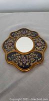 Front view of the decorative mirror showing black, gold, and floral design on the frame surrounding the mirror glass.
