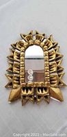 Front view of the small decorative ceramic mirror with golden glaze and sculptural frame