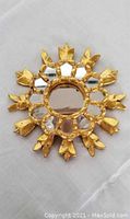 Front view of circular decorative mirror showing gold sunburst frame with multiple mirrored segments and central round mirror.