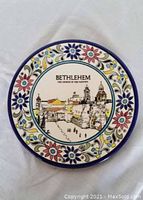 Front view of the glazed ceramic plate showing the colorful floral border and cityscape illustration of Bethlehem in the center.