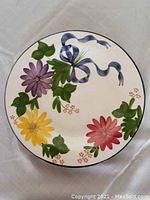 Top-down photo showing the full floral and ribbon design on the round ceramic plate.