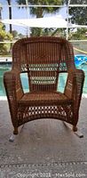 Front view of the brown woven rocking chair showing full structure and armrests