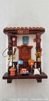 Front view of the wooden Colombian house facade showing door, columns, tiled roof, and toy decorations.