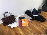 Wide shot showing all purses and scarves on wooden floor against wall