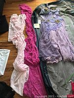 Full view of the light purple belly dancer costume laid out with two scarves, one pink and one fuchsia, shown on a wooden floor