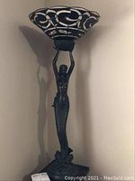 Full view of the 41-inch tall mermaid floor lamp with black mermaid base holding a large black and white art glass shade.