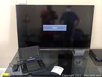 Front view of Vizio 40-inch TV on glass table with 'No Signal' displayed and Panasonic DVD player in front