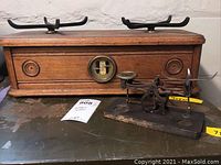 Photo showing two vintage scales: a large wooden box frame scale with metal balancing arms and a smaller metal scale on a wooden base.