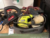 Photo showing three electric workman tools: Ryobi orbital sander with dust bag, Chicago Electric belt sander and Drill Master planer bundled together on shelf.