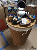 Photo of Talavera style ceramic bathroom accessories on wicker laundry basket, includes toothbrush holder, tissue holder, soap dishes, hairdryer, and magnifying mirror.