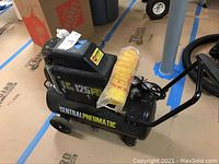 Full view of the Central Pneumatic 2 HP air compressor showing tank, wheels, handle, and attached air filter.