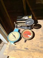 Four antique scales placed on a wooden surface, depicting the variety in size and design including metal and wood scales.
