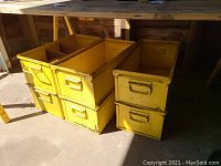 Six vintage yellow metal drawers stacked in two columns with visible front pull handles, showing signs of wear such as peeling paint and rust.