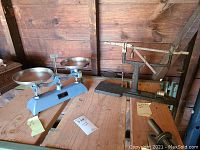 Photo showing two vintage scales on a wood surface, Central Scientific Cenco triple beam balance and Troemner scale.