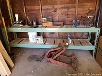 Front and side view of green metal framed work bench with wood slat shelves, showing tools on top shelf and wood shelves on lower level