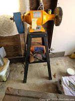 Front view of yellow Pit Bull 8-inch buffer mounted on black metal stand with grinding wheel.