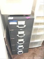 Front view of a gray 5-drawer metal file cabinet with each drawer labeled and featuring silver handles.