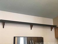 Full view of the long wall shelf mounted above refrigerator showing length and placement on wall.