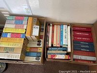 Three boxes with assorted books including classic American literature by Hemingway and Steinbeck visible