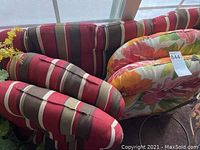 Photo showing multiple striped cushions with red, black, beige, and white vertical stripes alongside floral cushions on a window seat.