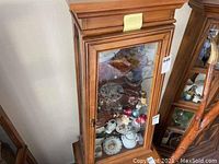 Front view of the wooden display cabinet with glass doors showing various items inside.