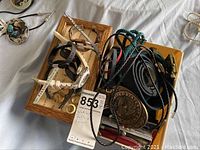 Watches, belts including one with United States emblem buckle, and knives displayed on fabric surface.